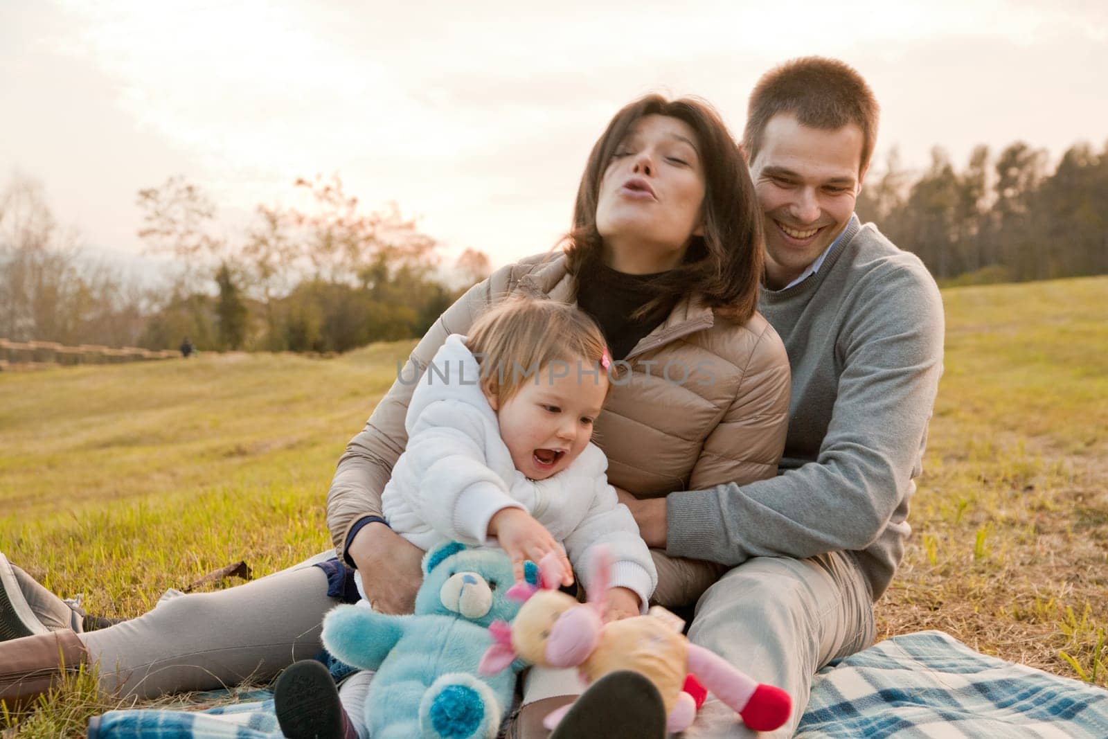 Mother Father and their little son having happy times together in autumn outdoor in the green wood and grass