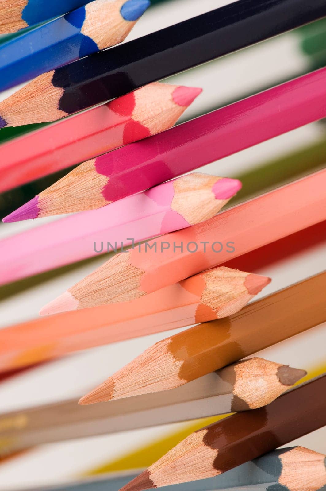 Close-up in oblique view over cross stacked crayons in the colors of the color circle with selective sharpness