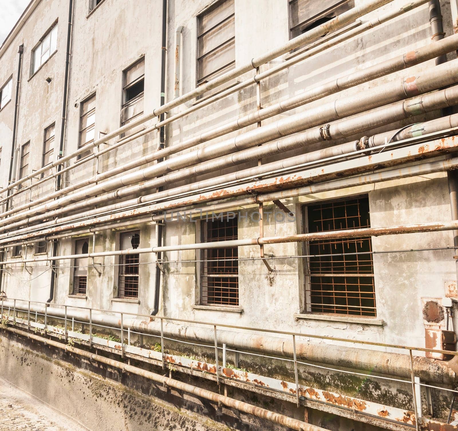 Old pipes on the wall outside of an old abandoned factory.