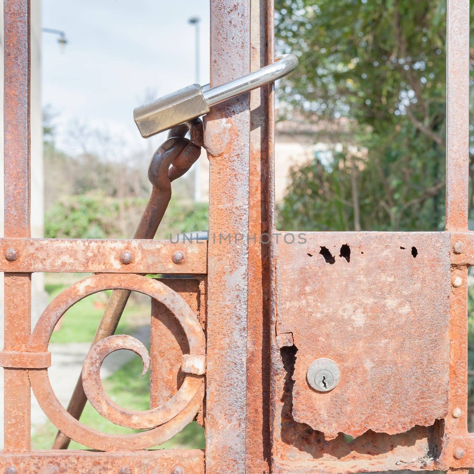 Rusty metal gate closed with padlock - concept image
