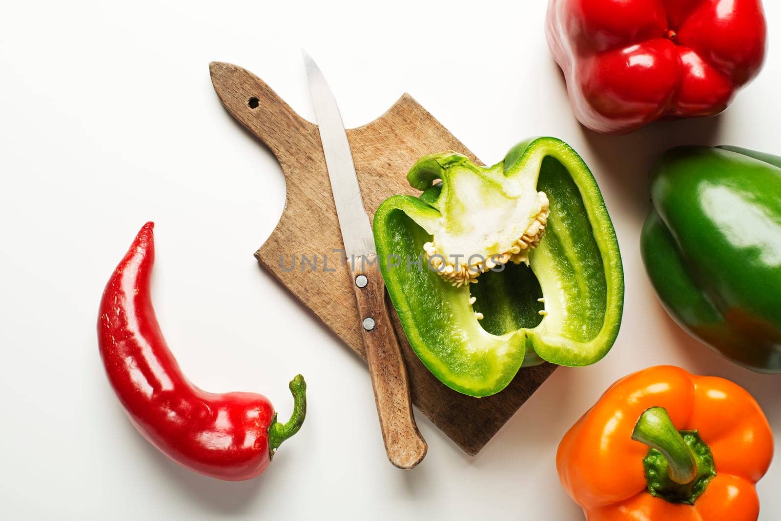 Red, green and orange bell peppers on white background.