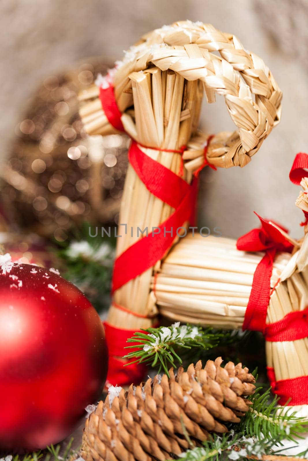 red Christmas baubles between cones and fir branches covered with snow as macro detail