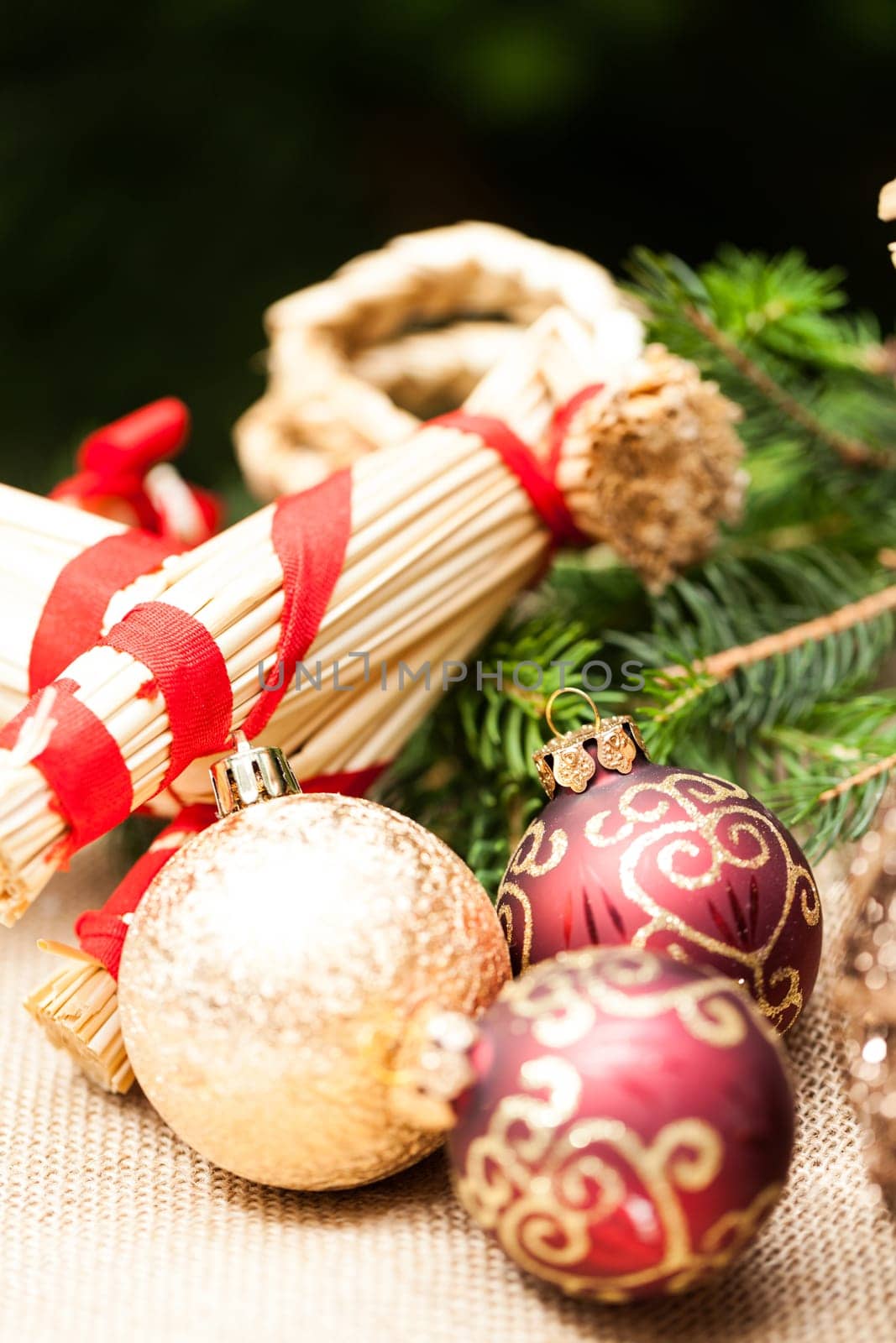 Decoration for Christmas with red and gold Christmas tree balls in front of green fir branches in the background