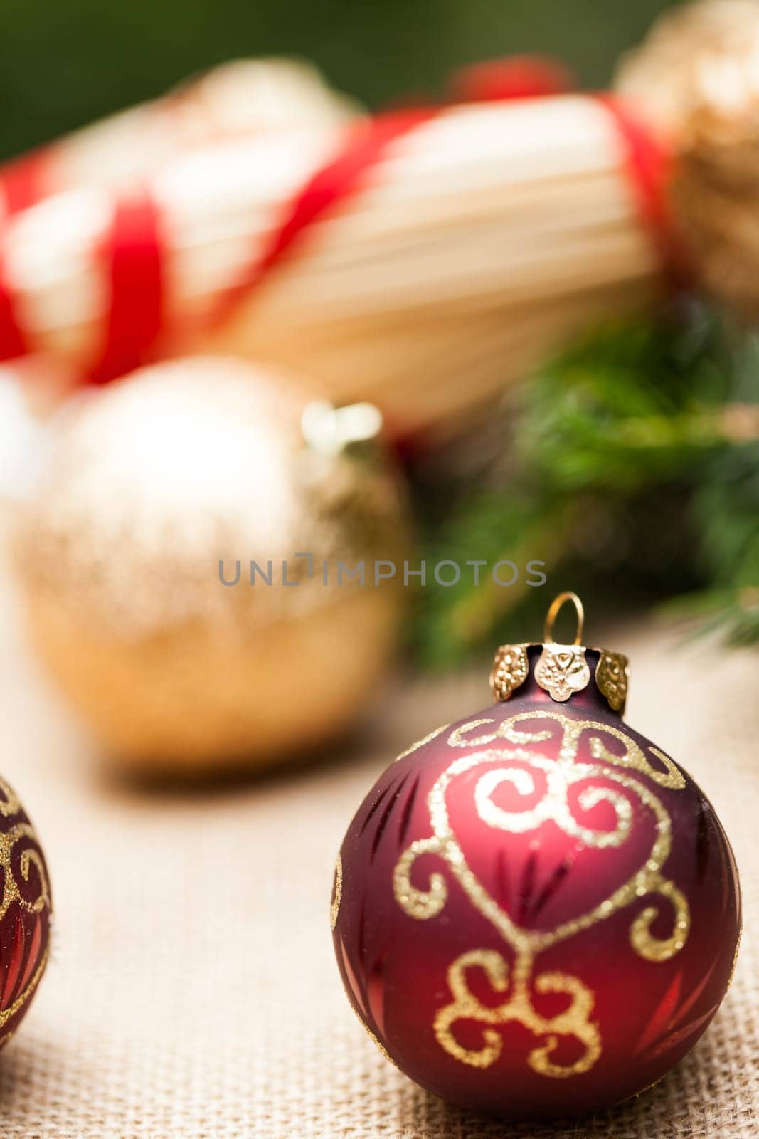Decoration for Christmas with red and gold Christmas tree balls in front of green fir branches in the background