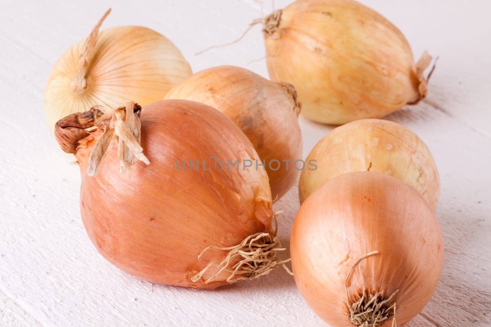 Fresh onions with brown peel on a rustic wooden board as close-up