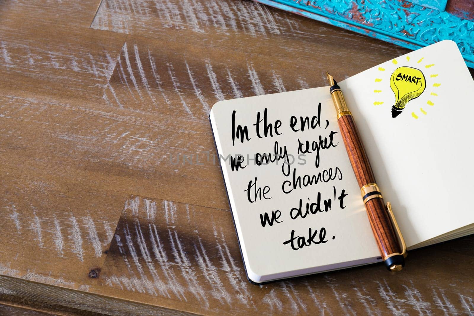 Handwritten text In the end, we only regret the chances we didn’t take with fountain pen on notebook. Concept image with copy space available.
