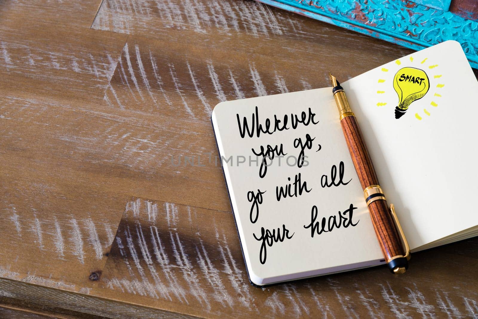 Handwritten text Wherever you Go, Go With All Your Heart with fountain pen on notebook. Concept image with copy space available.