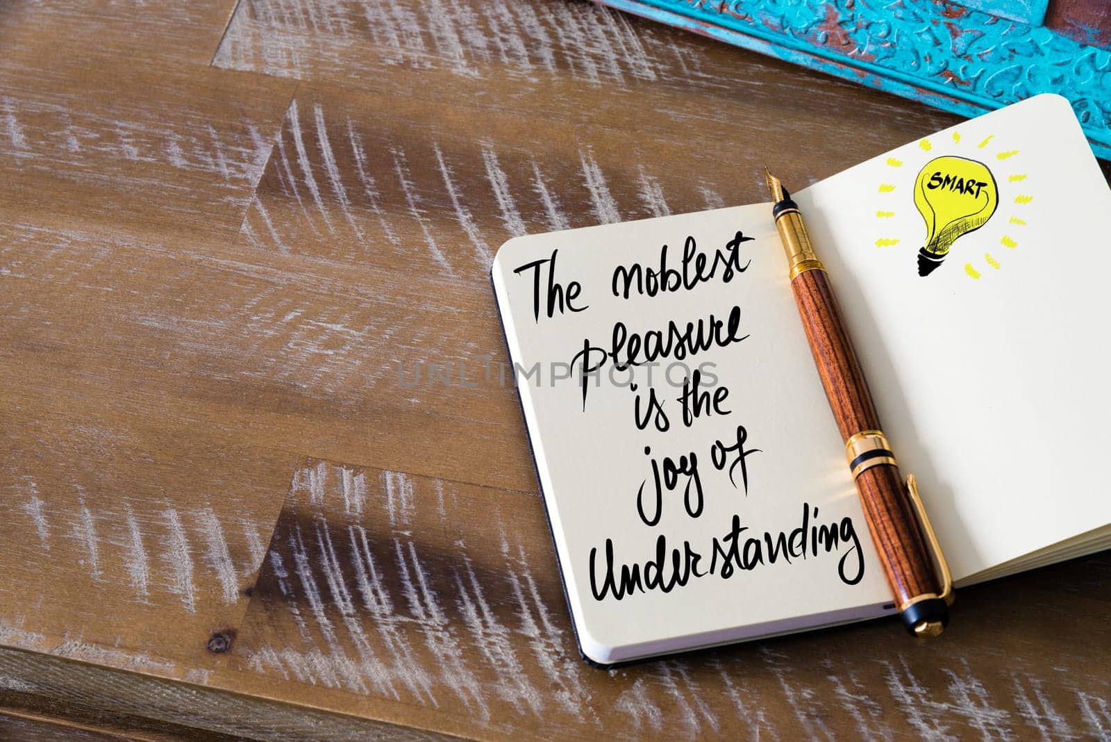 Handwritten text The noblest pleasure is the joy of understanding with fountain pen on notebook. Concept image with copy space available.