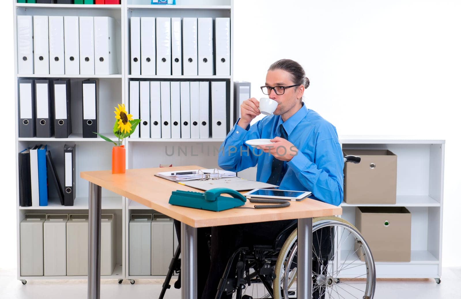 disabled business man in wheelchair is drinking coffee