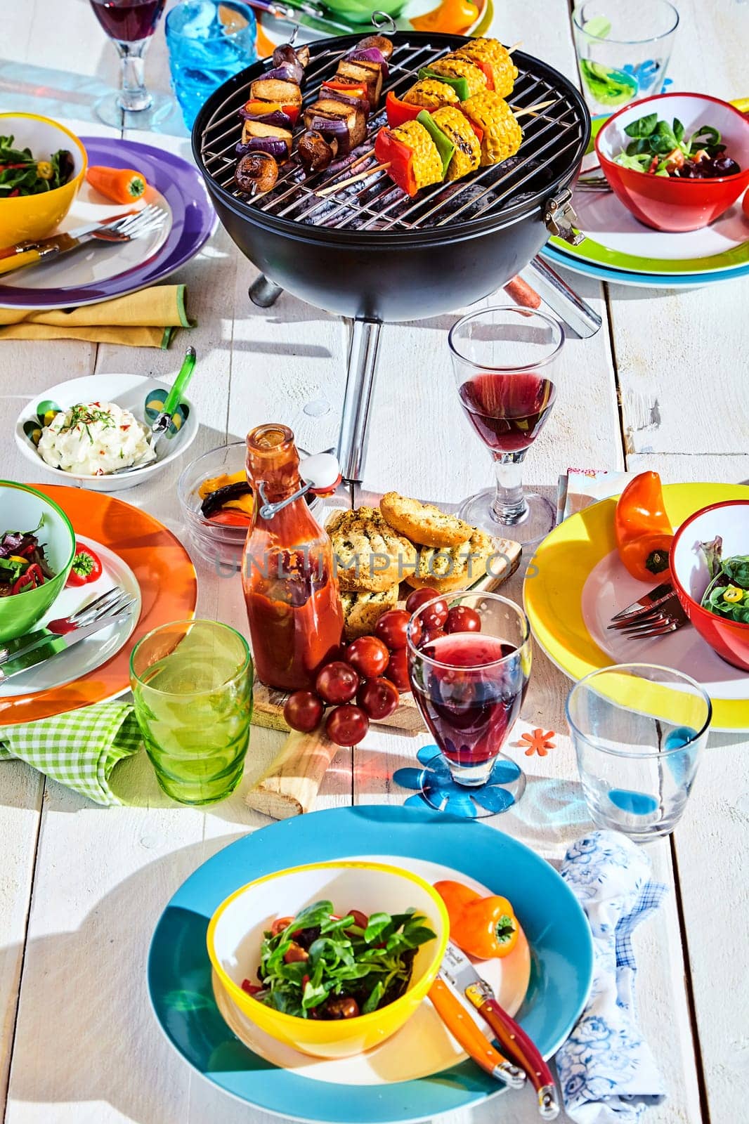 Well Laid summer table with colorful dish and plates and brazier on white background with vegan bbq skewers