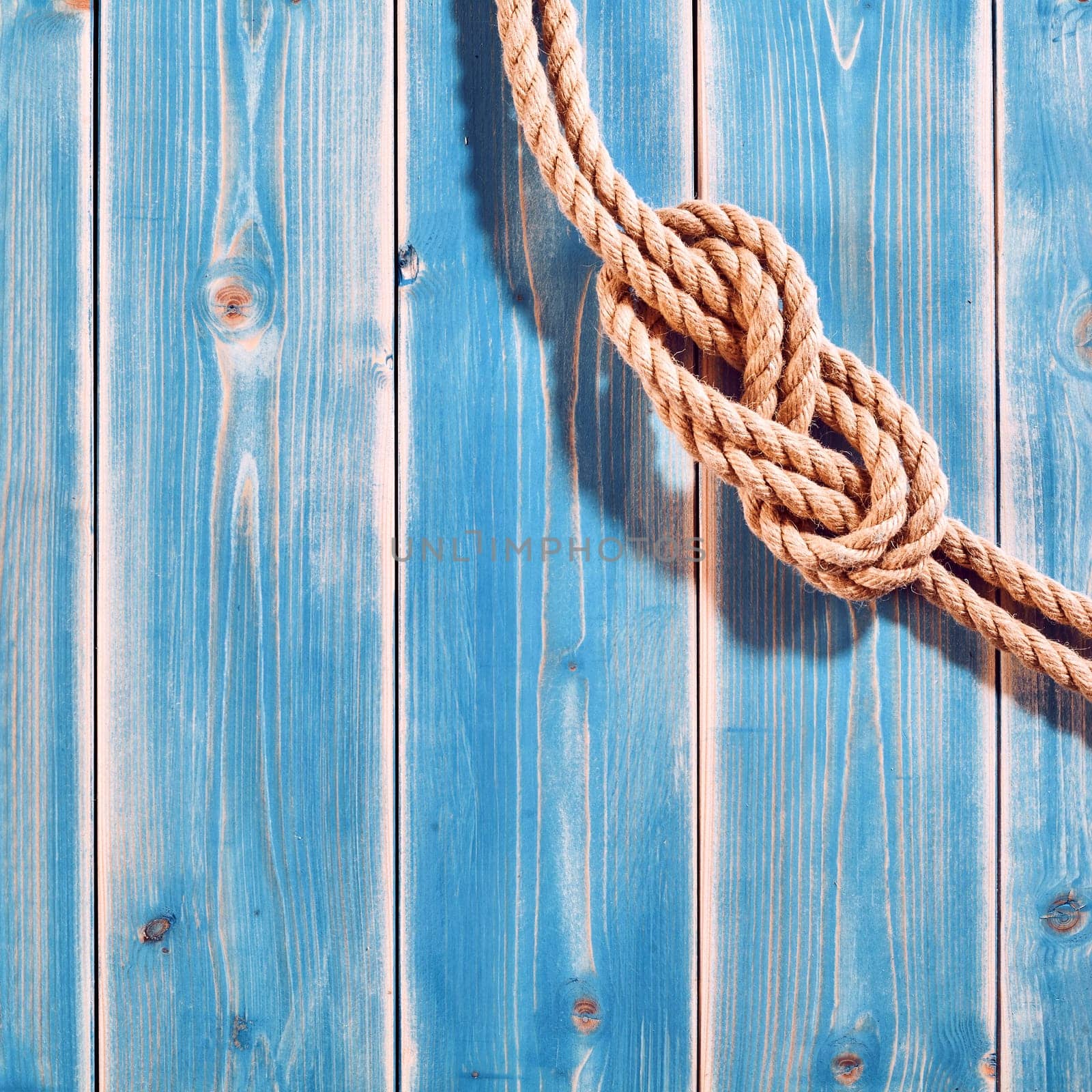 Nautical Themed Background - High Angle Still Life of Double Figure Eight Knot in Natural Rope Across Corner of Blue Painted Wood Plank Background with Copy Space