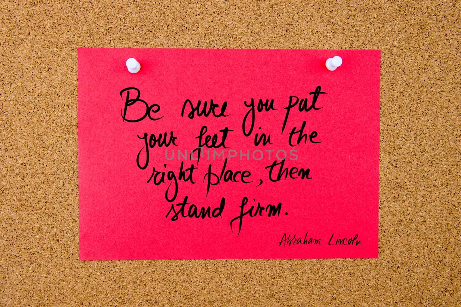 Quote Be Sure You Put Your Feet In The Right Place, Then Stand Firm by Abraham Lincoln, written on red paper note pinned on cork board with white thumbtacks, copy space available