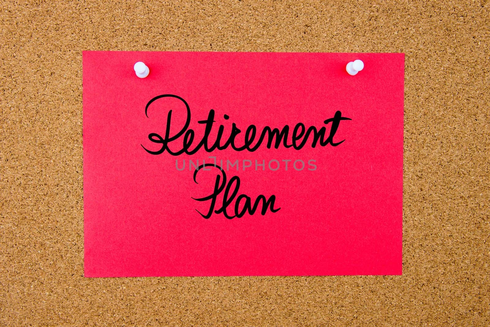 Red paper note with handwritten text Retirement Plan pinned on cork board with white thumbtacks