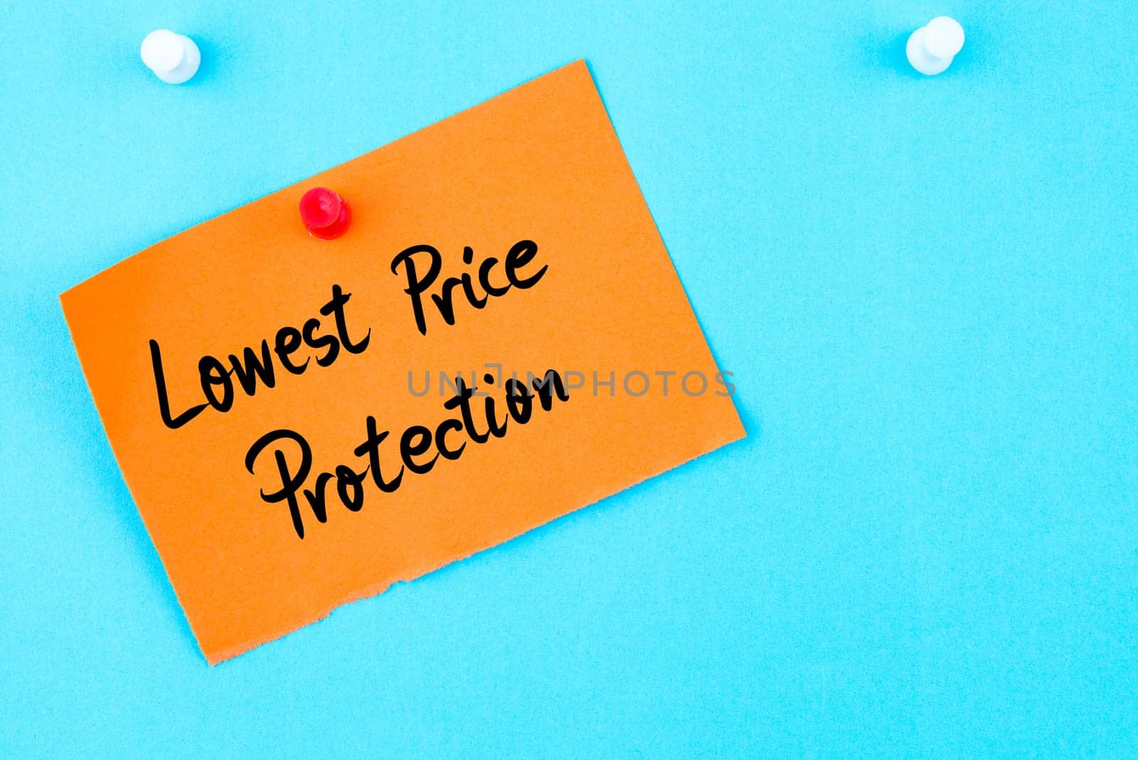 Lowest Price Protection written on orange paper note pinned on cork board with white thumbtack, copy space available