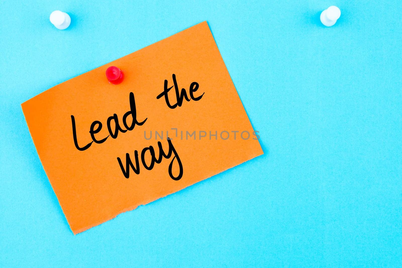 Lead The Way written on orange paper note pinned on cork board with white thumbtack, copy space available
