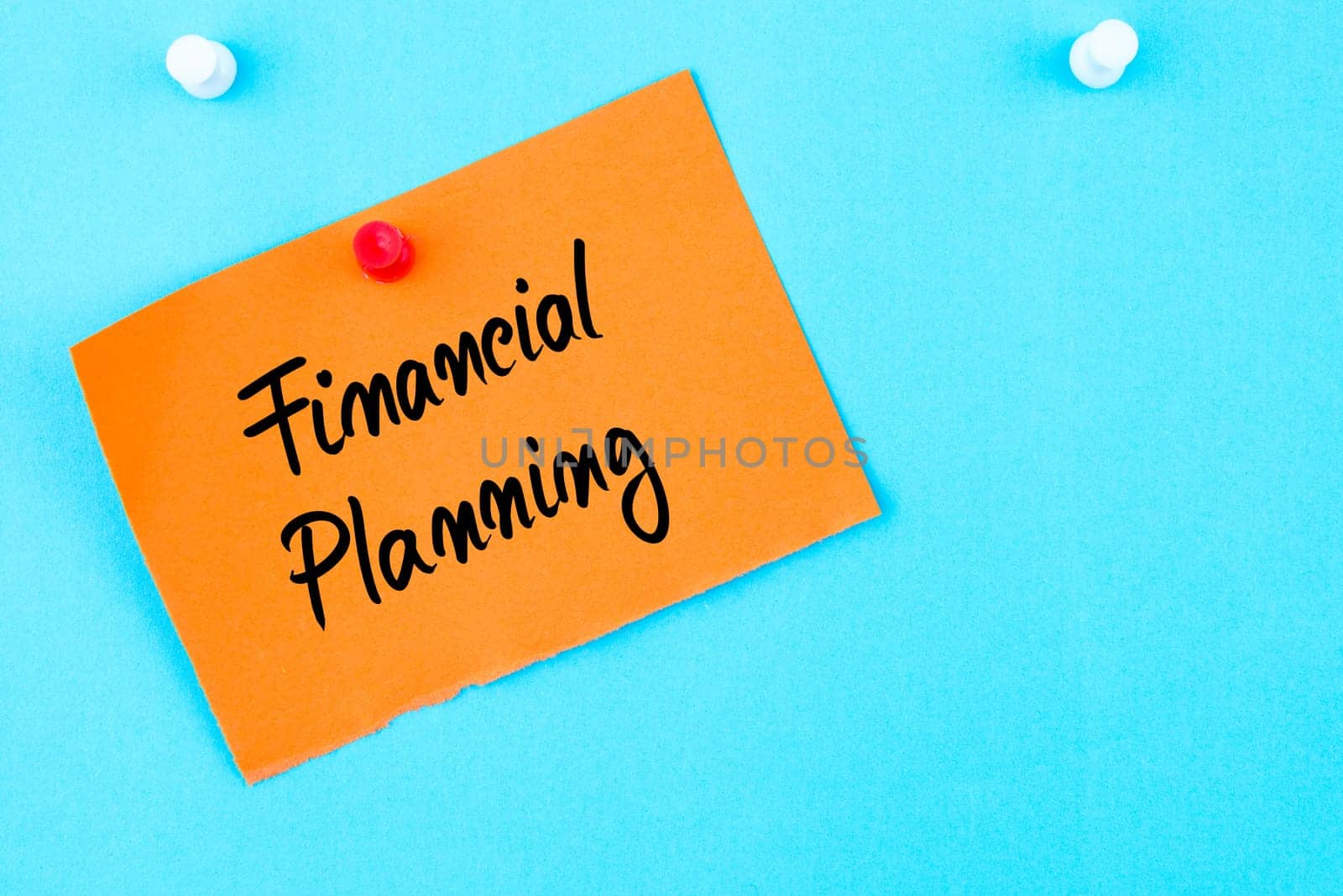 Financial Planning written on orange paper note pinned on cork board with white thumbtack, copy space available