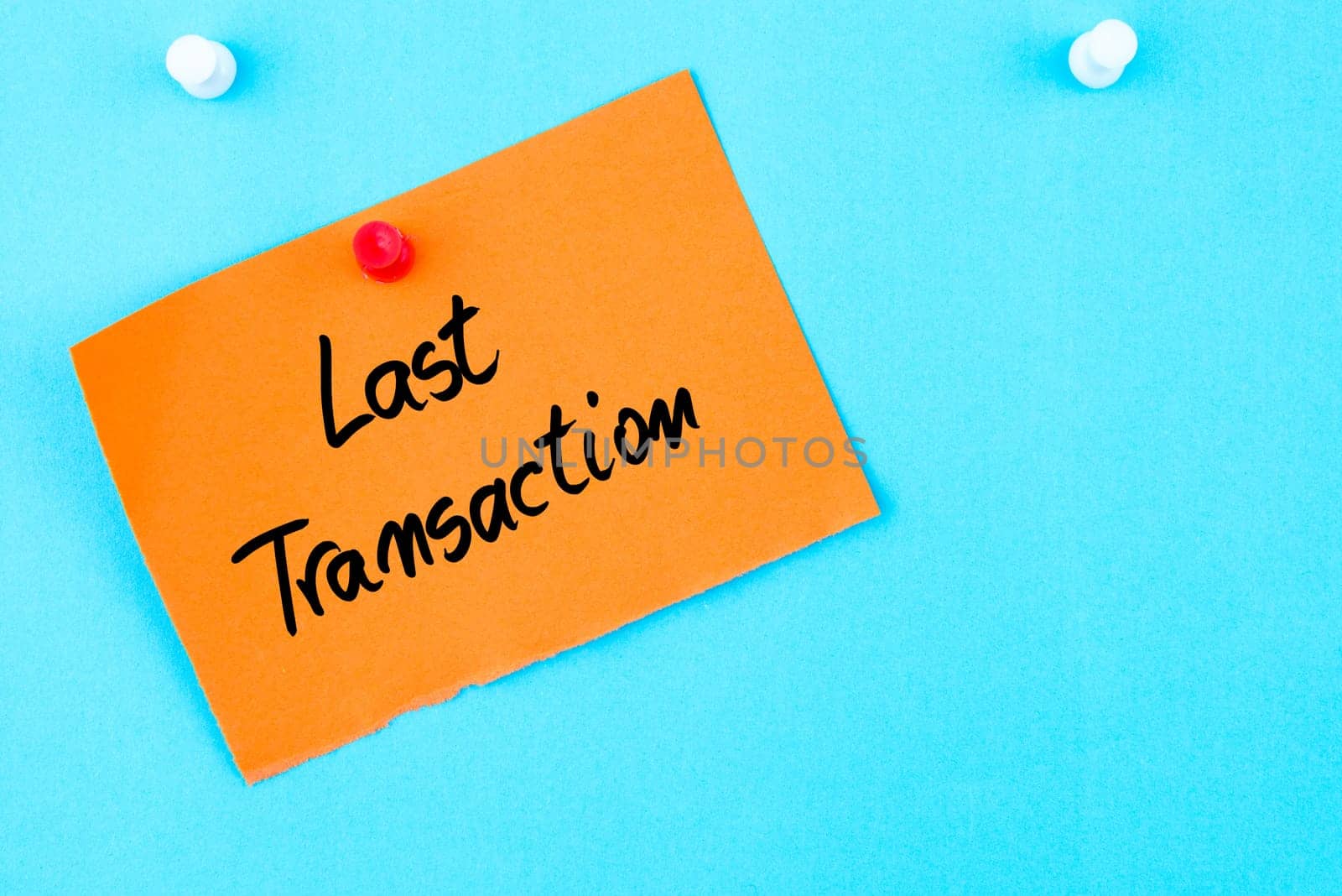 Last Transaction written on orange paper note pinned on cork board with white thumbtack, copy space available