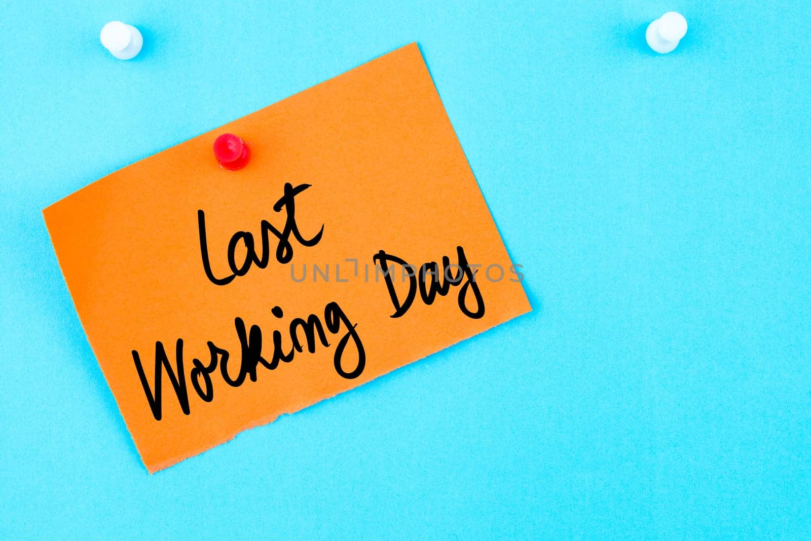 Last Working Day written on orange paper note pinned on cork board with white thumbtack, copy space available