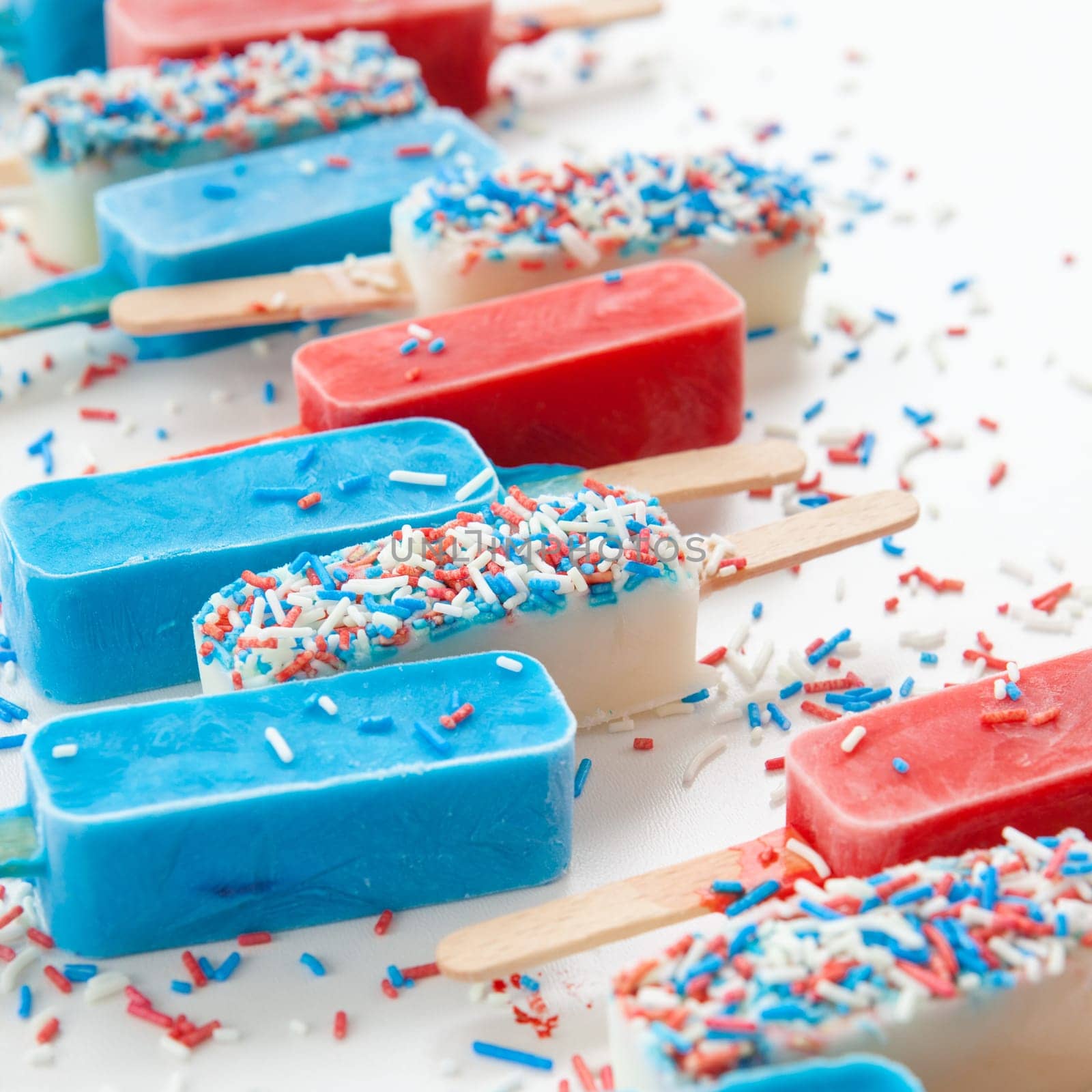 Colorful popsicles with sugar sprinkles on white