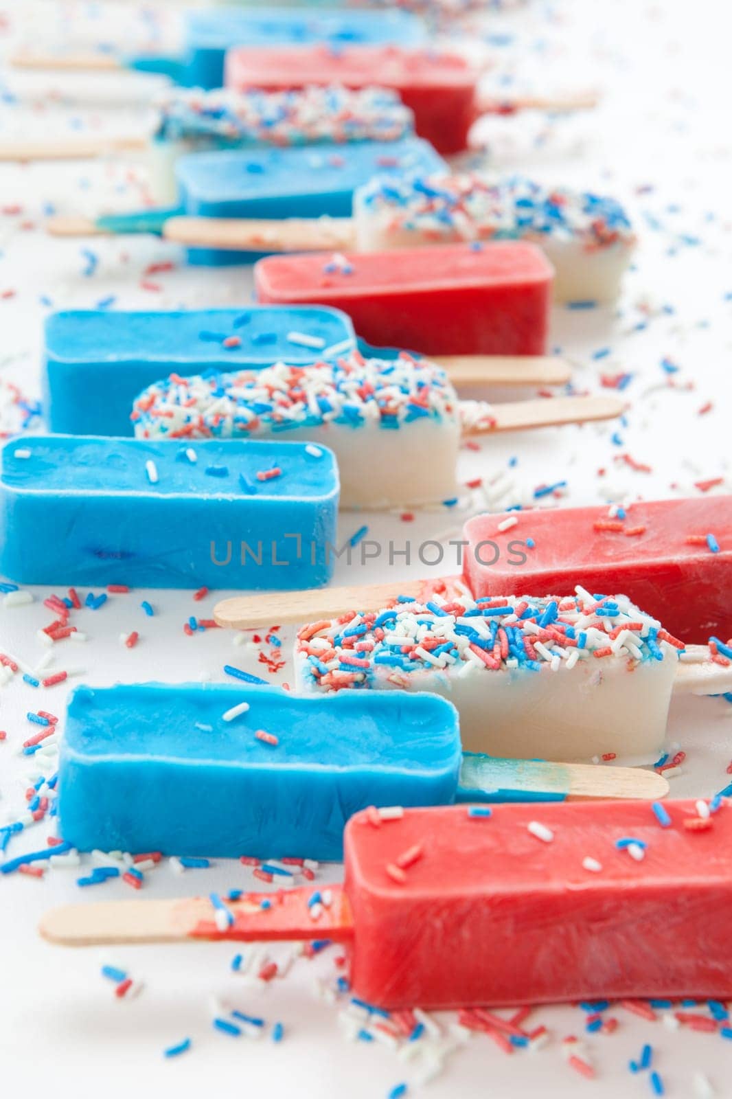 Colorful popsicles with sugar sprinkles on white