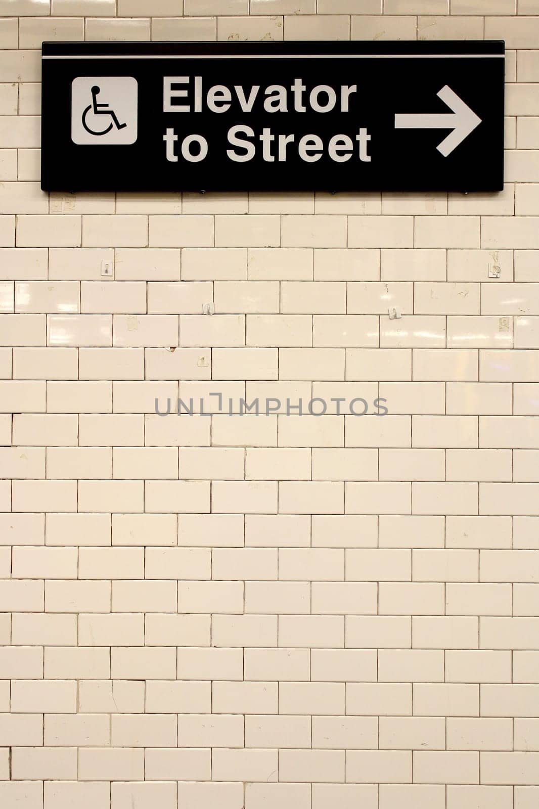New York City Station subway directional sign on tile wall. The NYC Subway is one of the oldest and most extensive public transportation systems in the world, with 468 stations.