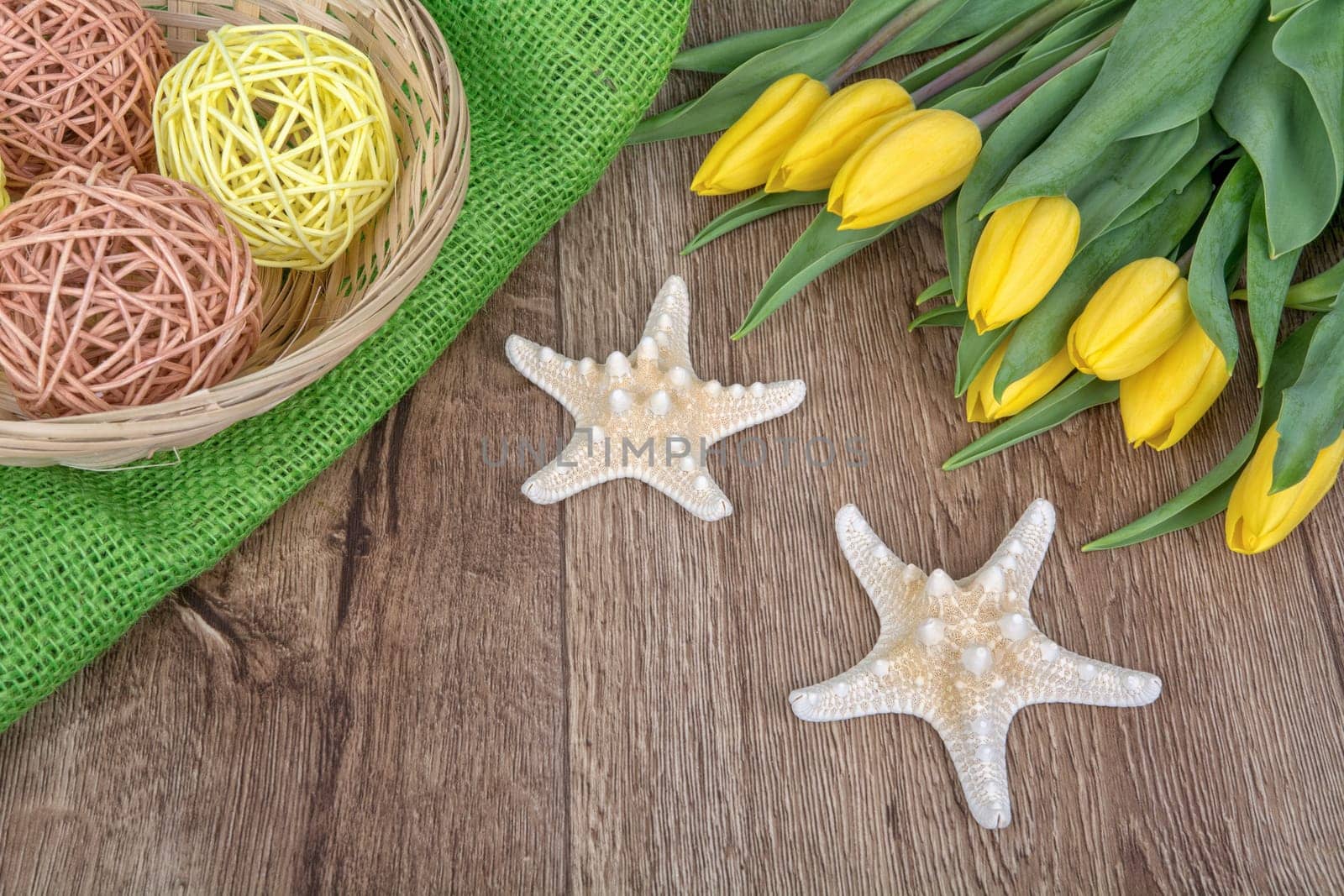 Starfishes and yellow tulips on a wooden background