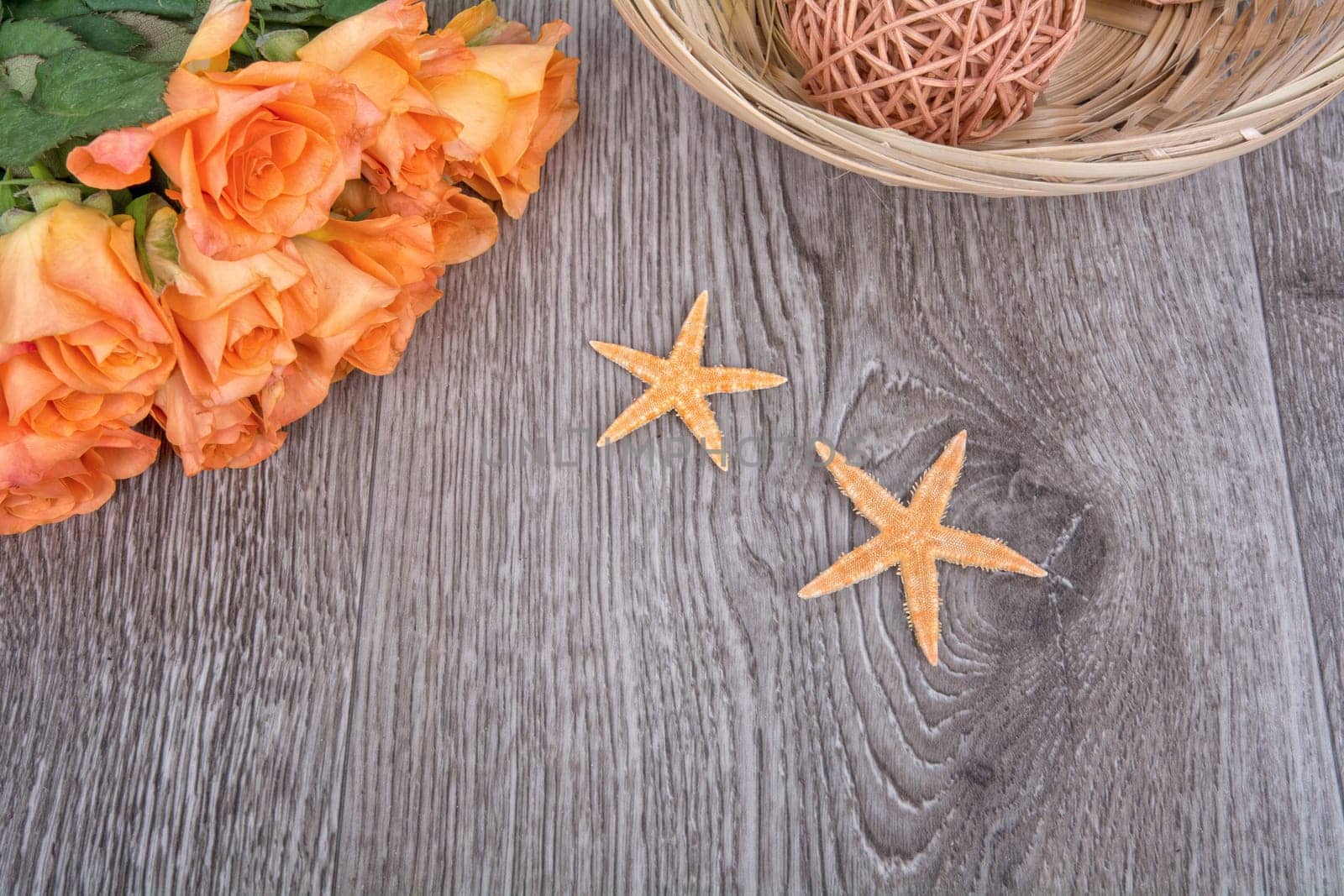 Orange starfishes and orange roses on a wooden background