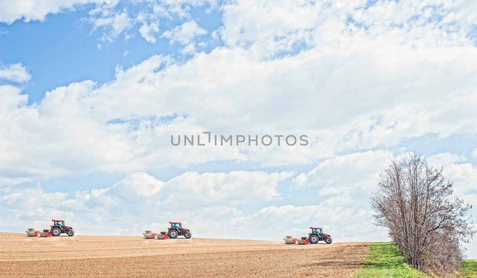 Farm work. Tractor compresses the soil after planting with rollers.