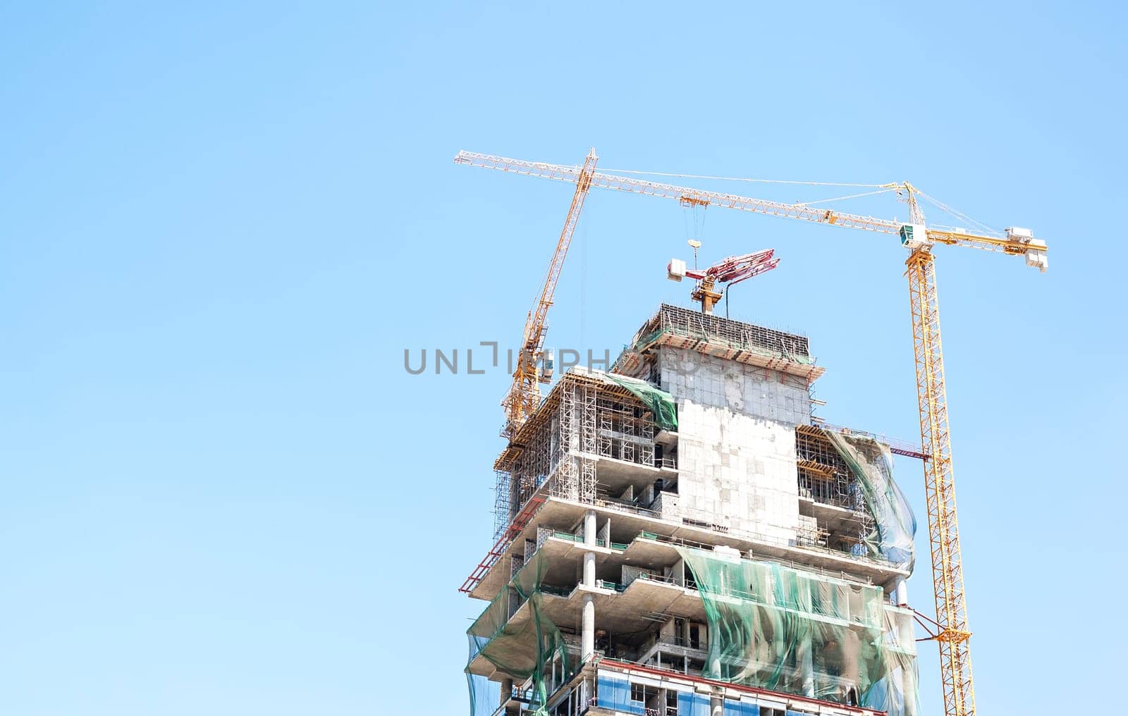 Building crane and building under construction against blue sky