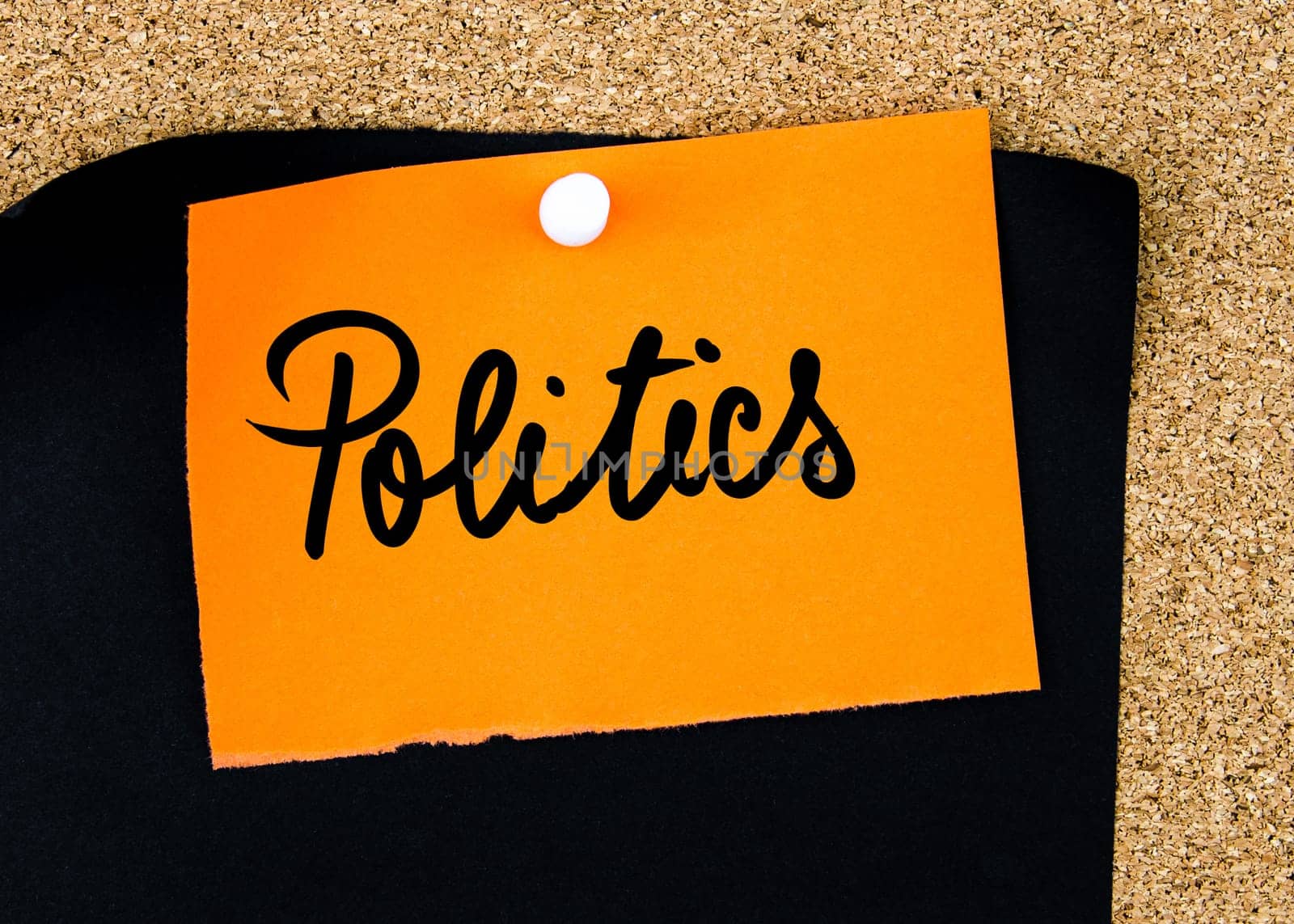 Politics written on orange paper note pinned on cork board with white thumbtacks, copy space available