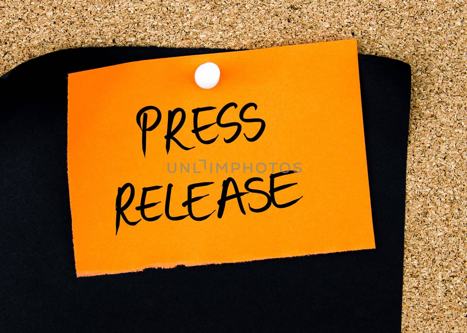 PRESS RELEASE written on orange paper note pinned on cork board with white thumbtacks, copy space available