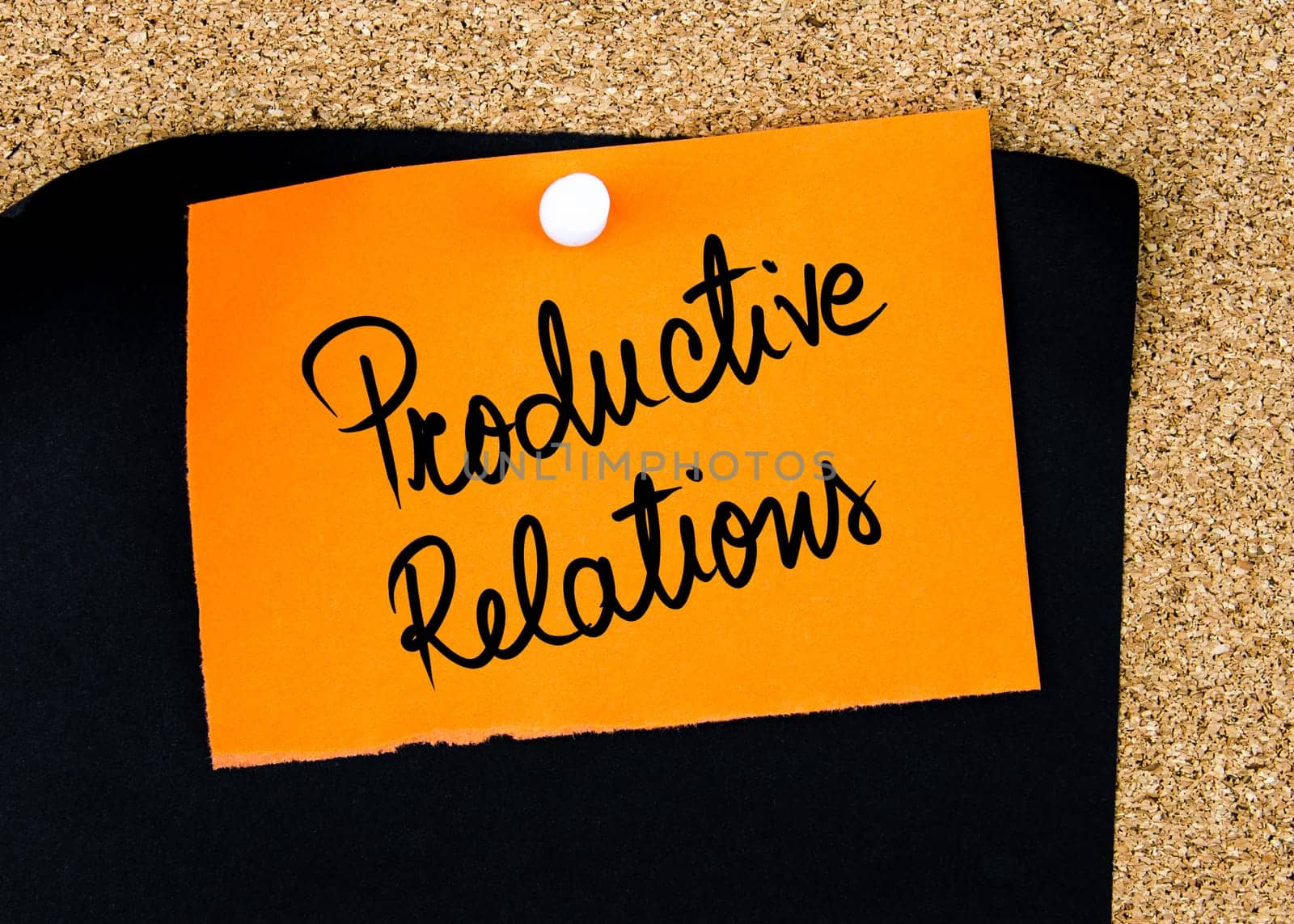 Productive Relations written on orange paper note pinned on cork board with white thumbtacks, copy space available