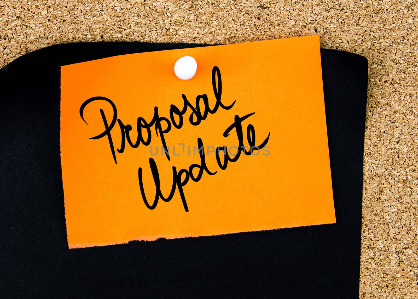 Proposal Update written on orange paper note pinned on cork board with white thumbtacks, copy space available