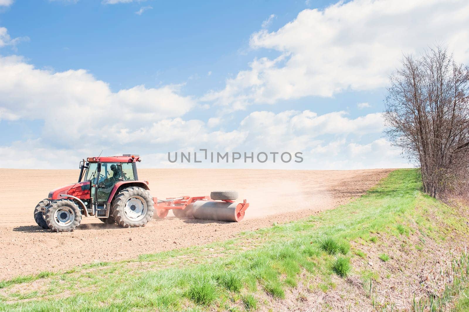 Farm work. Tractor compresses the soil after planting with rollers.