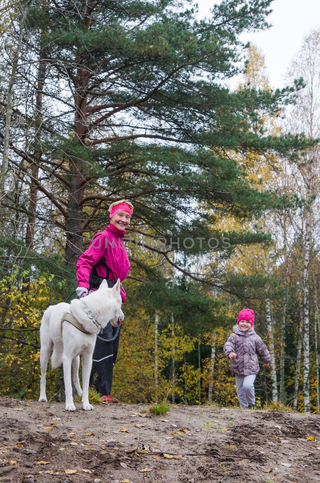Granny with her granddaughter and a dog walk in autumn Park