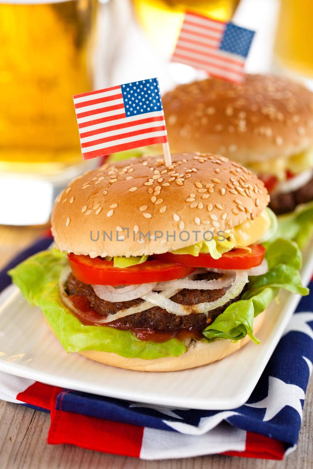 Beer and two tasty hamburgers with little American flags on top.