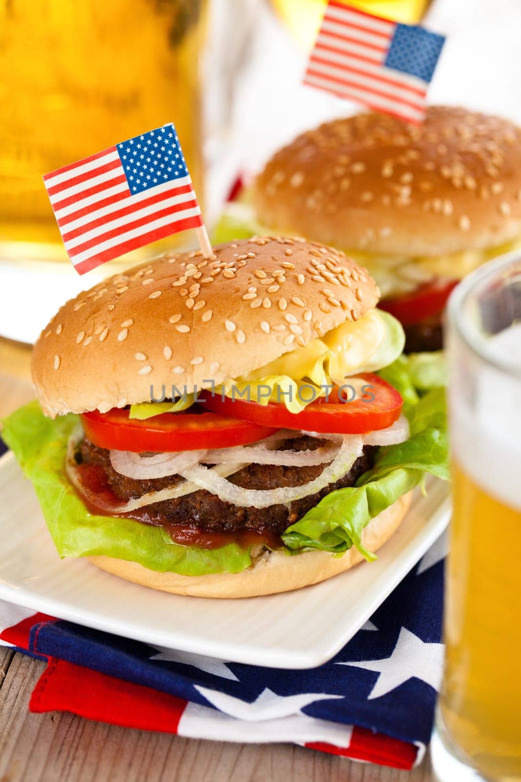 Beer and two tasty hamburgers with little American flags on top.