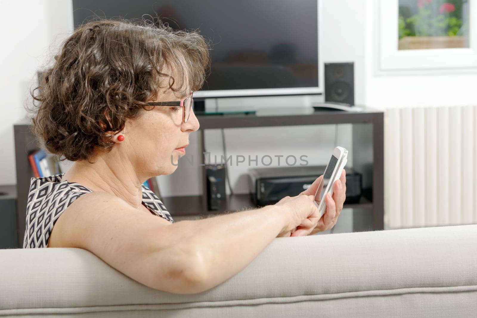 a beautiful mature woman with phone on the couch