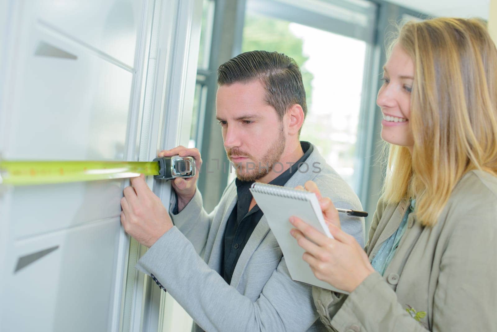 man measuring a fitted cupboard