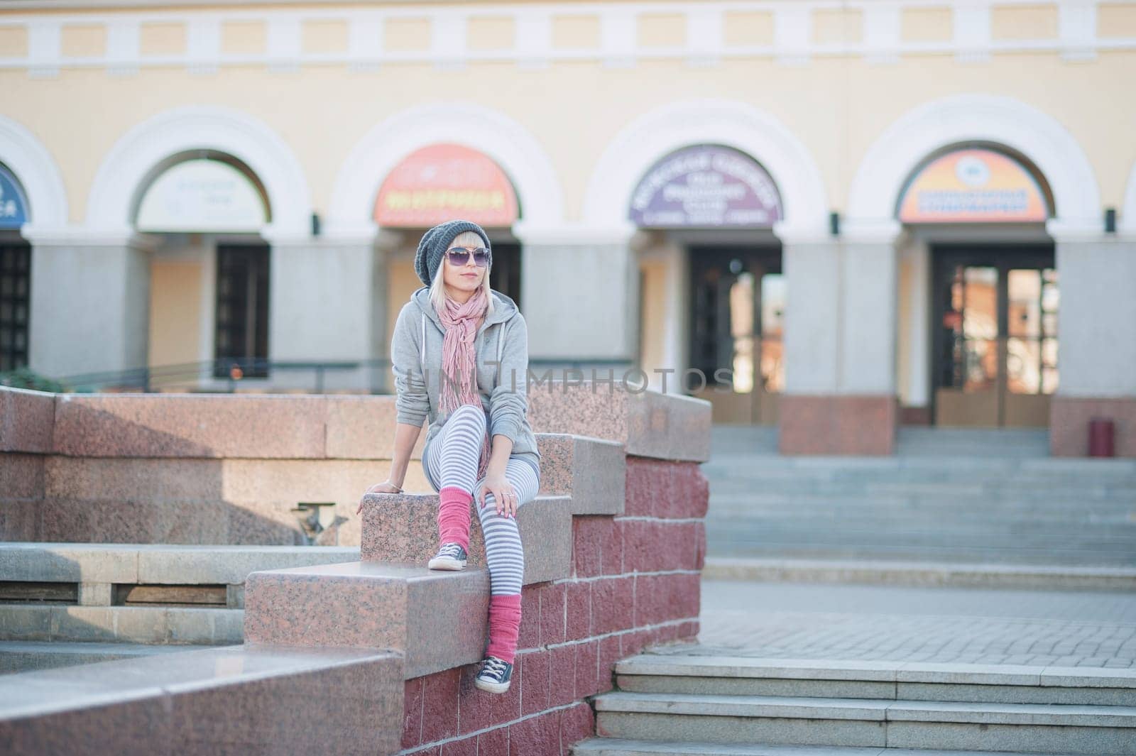 Stylish and fashionable girl on a walk around the city. Black and white knitted hat sneakers, pink socks. Outerwear, warm clothing. Fashionista. clothing items. Autumn clothes.