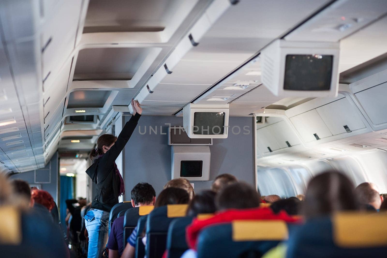 girl puts hand baggage on Board the aircraft
