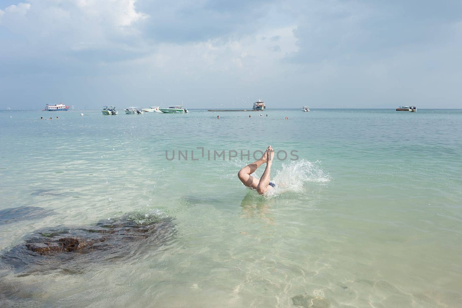 people jumping into the sea, against the backdrop of yachts, motor boats and scooters