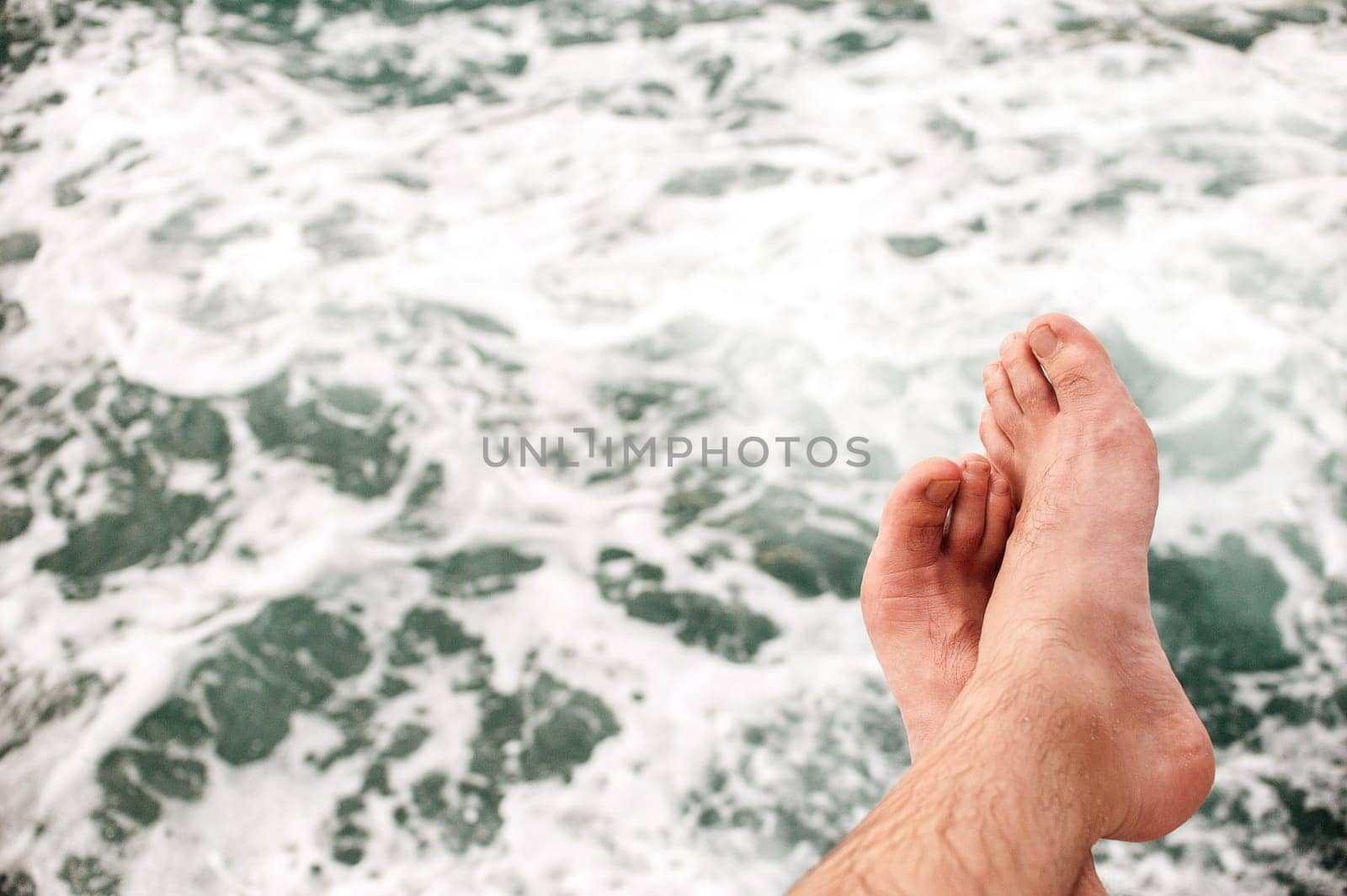 No person Unrecognizable man&#39 s legs, sitting on the edge of the pontoon, outdoors against the sea, texture