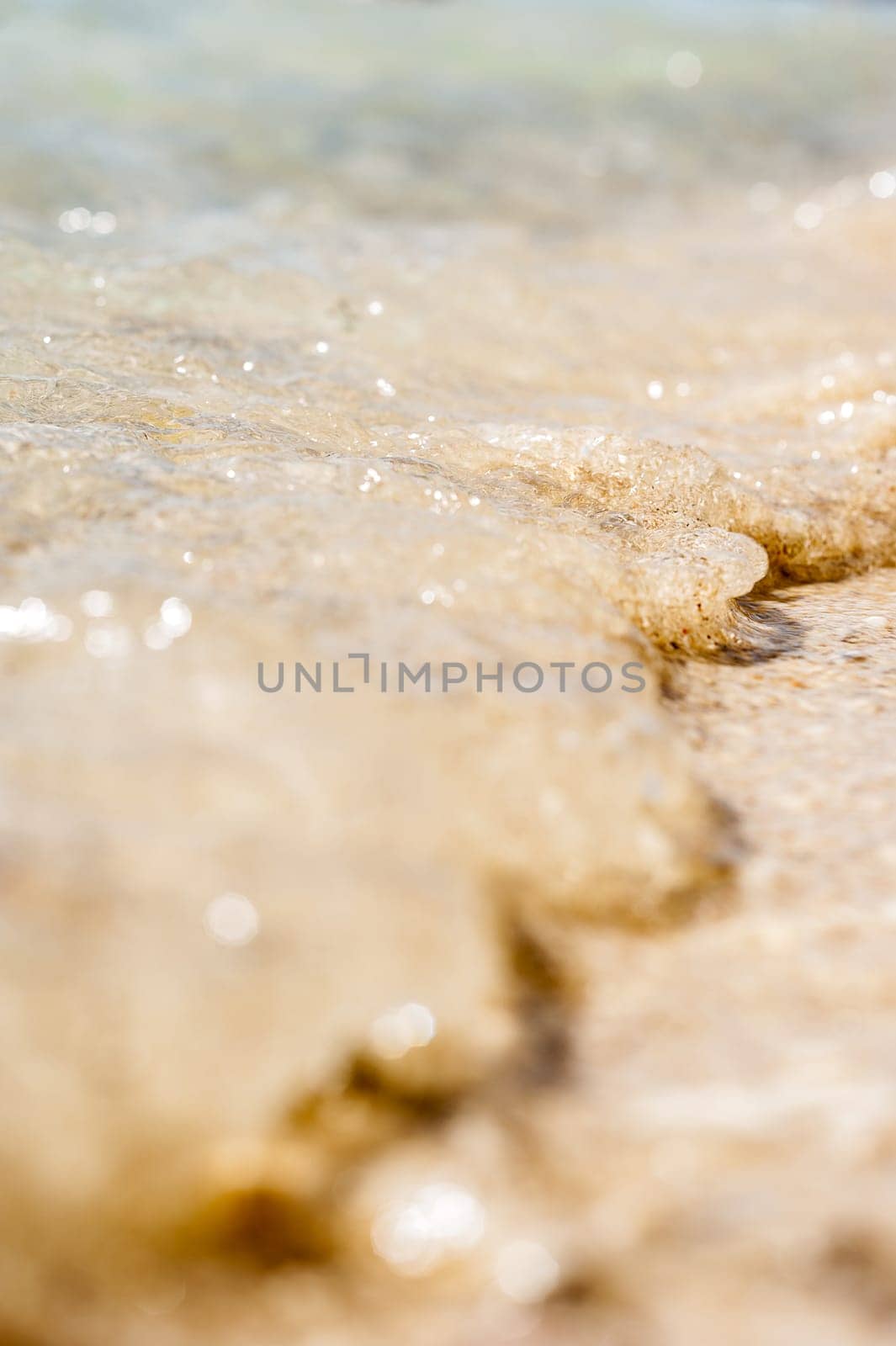 small wave of the sea, throw small, yellow sand on the beach. vertical, large, macro, bokeh