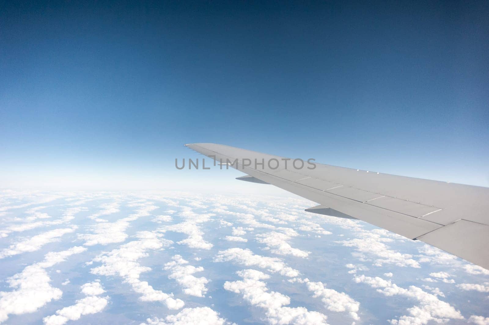 airplane wing above the clouds, blue sky
