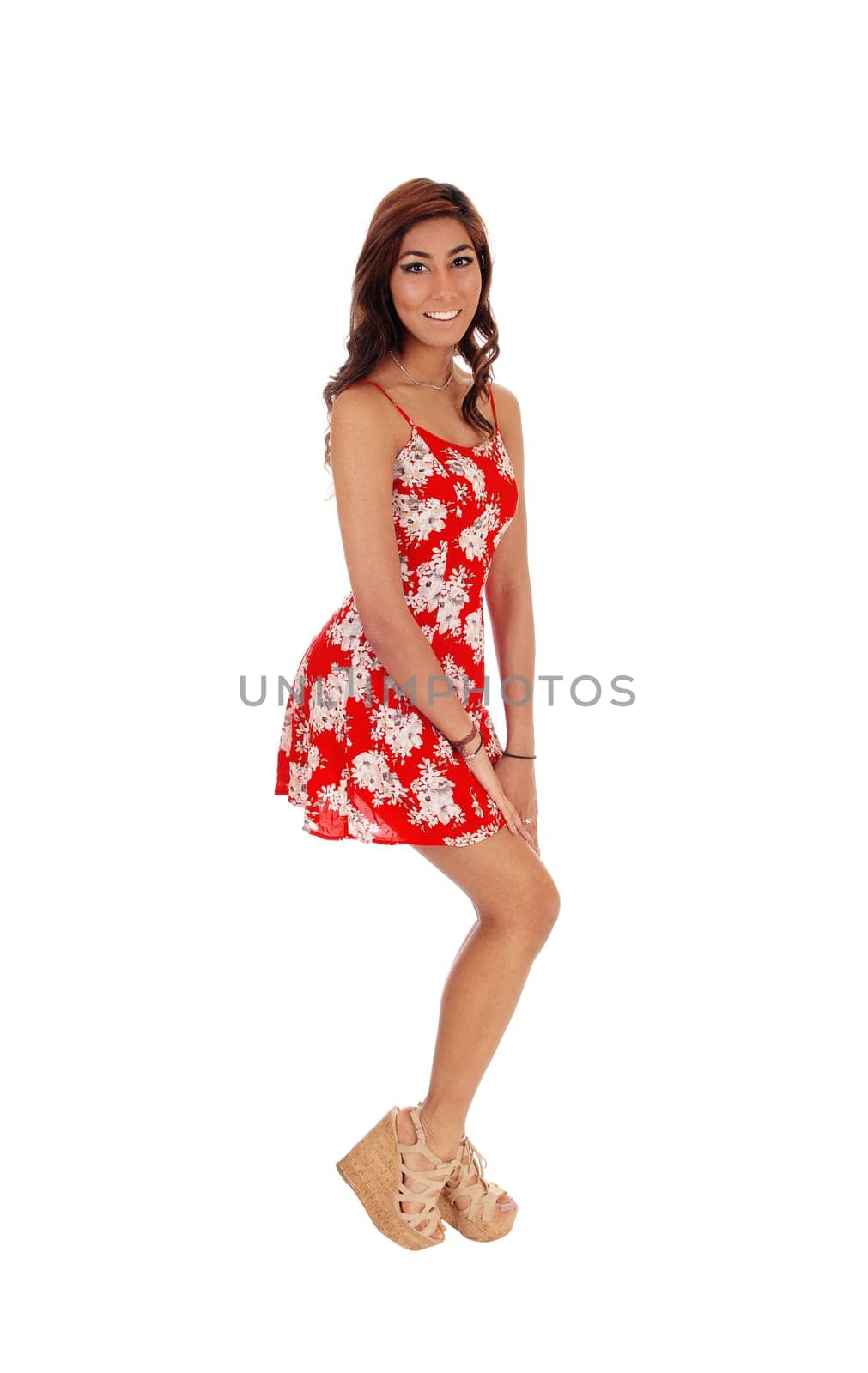 A lovely happy young woman standing in profile in a red dress, .smiling, isolated for white background..