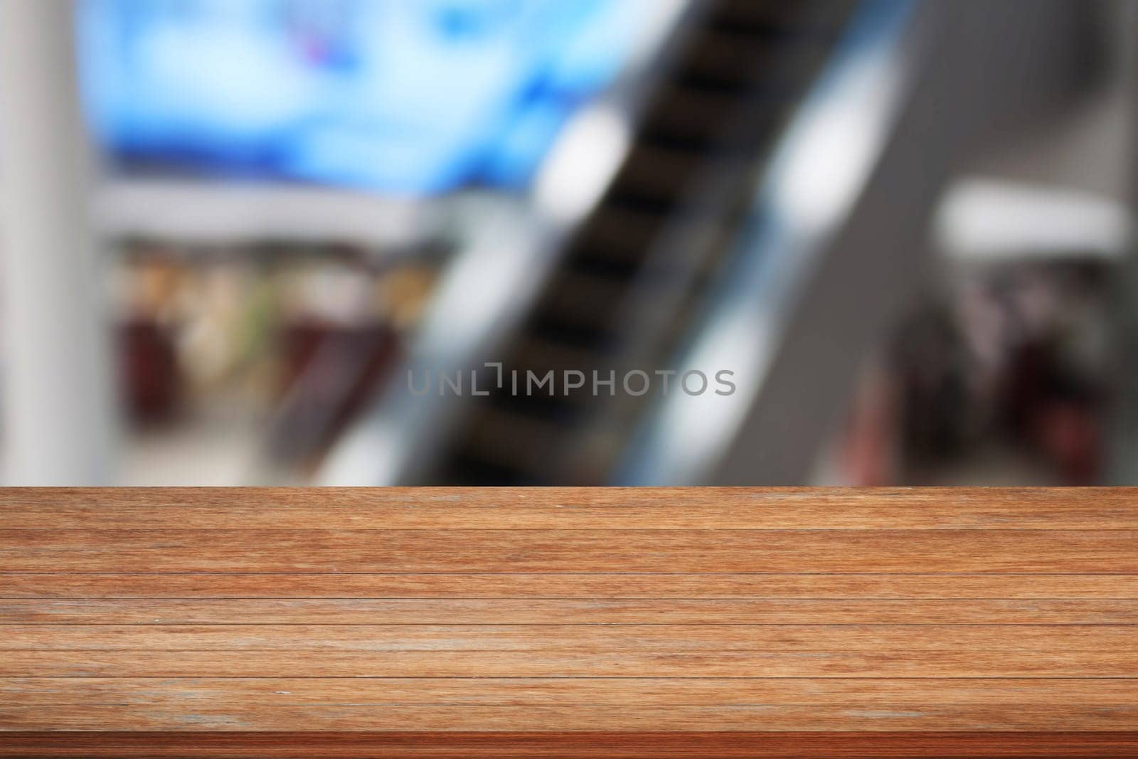 Wooden table top with blurred background of escalator in Airport