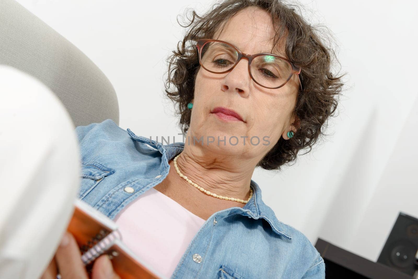 woman of middle age reads, sitting on the sofa