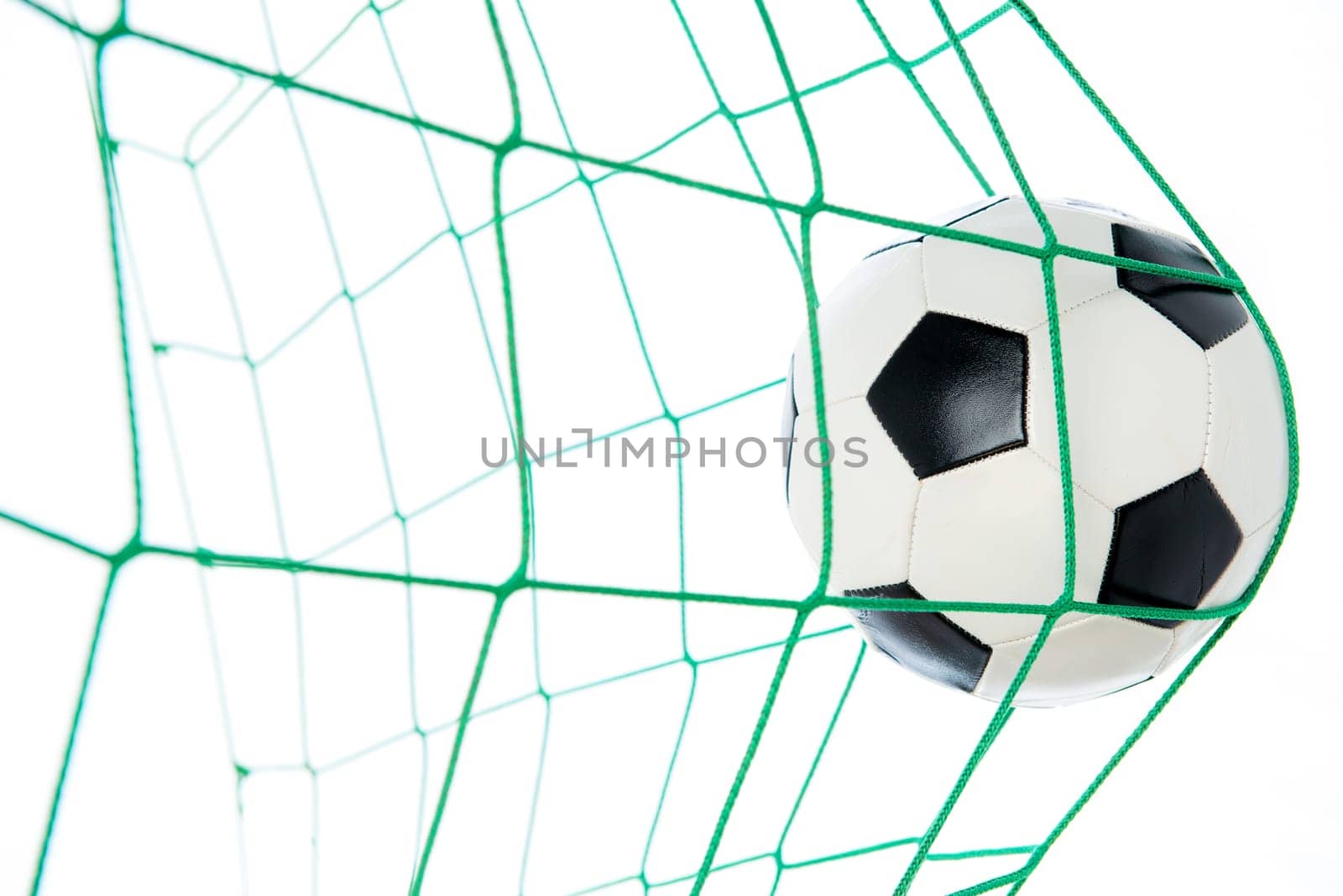 soccer ball in green goal in front of white background