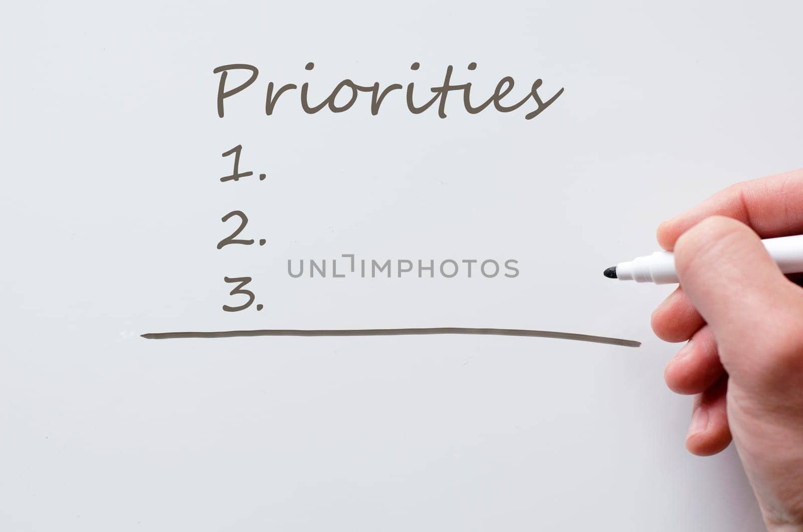 Human hand writing priorities on whiteboard